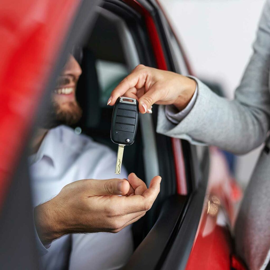 Car saleswoman giving man keys to his new car